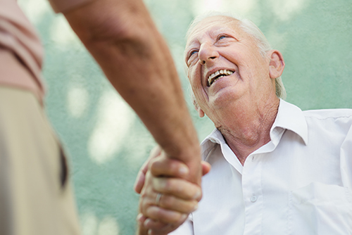 Elderly man looking up at doctor shaking his hand